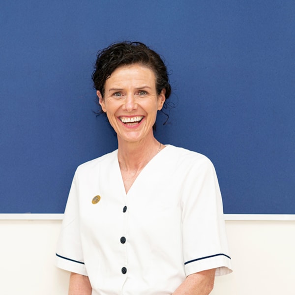 Female nurse standing in front of a noticeboard and smiling